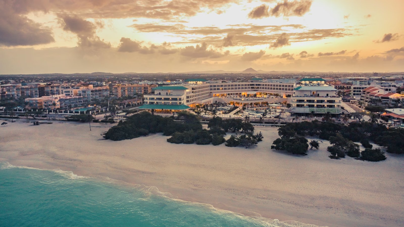 Eagle Beach Aruba at sunset: white sand, turquoise water and a beachfront resort seen from above